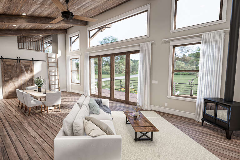 The living room in a Modern Farmhouse style home design features pine wood floors and an open concept with plenty of natural light.