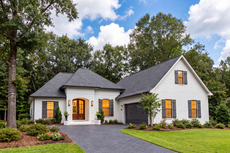 White French Country, Angled Front Elevation, brick siding, dark shutters, arched entry, lit windows, paved driveway. House Plan # 041-00109 Digital Rendering by America's Best House Plans, Inc.