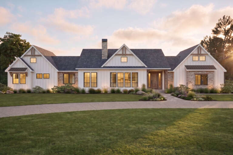 Front view of a white house in Modern Farmhouse style, board-and-batten siding, stone accents, and gabled rooflines. House Plan # 7011-00013