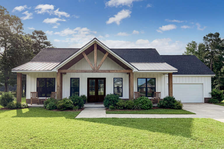White Modern Farmhouse, Front Elevation, board-and-batten siding, timber trusses, metal roof accents, lush landscaping. House Plan # 5105-00016 Digital Rendering by America's Best House Plans, Inc.
