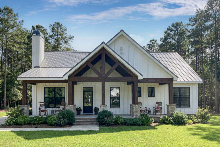 White Modern Farmhouse, Front Elevation, board-and-batten siding, metal roof, timber porch, stone piers, rocking chairs. House Plan # 009-00519 Digital Rendering by America's Best House Plans, Inc.