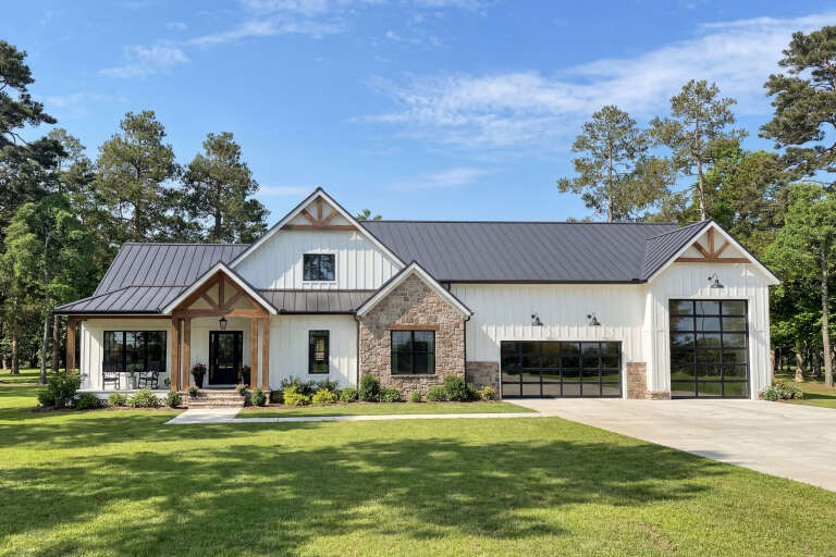White Barndominium, Front Elevation with board-and-batten siding, stone accents, metal roof, timber beams, glass garage. House Plan # 009-00522 Digital Rendering by America's Best House Plans, Inc.