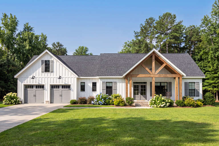 White Modern Farmhouse, Front Elevation with board-and-batten siding, timber porch, grey shutters, and lush landscaping. House Plan # 009-00526 Digital Rendering by America's Best House Plans, Inc.