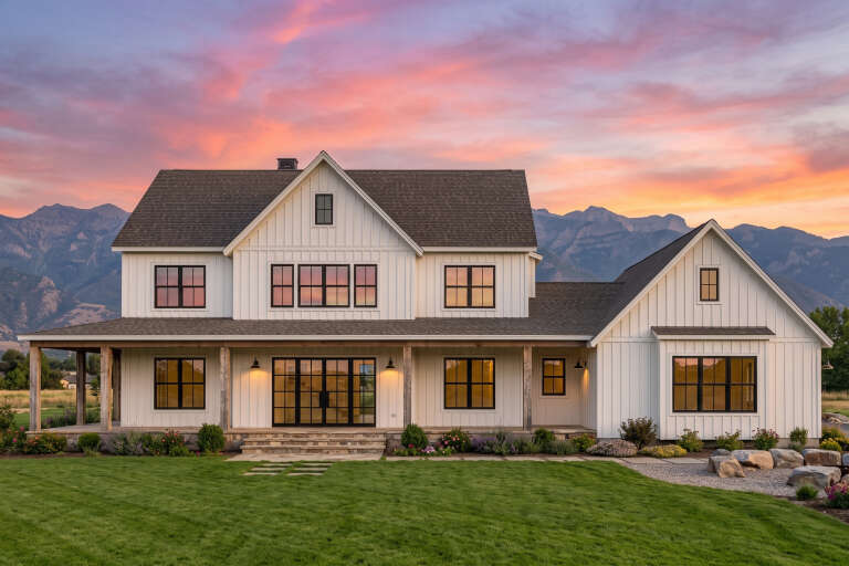 White Modern Farmhouse, Front Elevation at sunset, board-and-batten siding, stone porch, black windows, warm wall lights. House Plan # 7983-00202 Digital Rendering by America's Best House Plans, Inc.