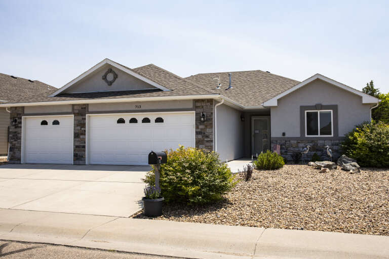 Grey Traditional, Angled Front Elevation, stucco and stone siding, white garage doors, concrete driveway, gravel yard. House Plan # 5244-00029 Digital Rendering by America's Best House Plans, Inc.