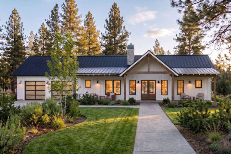White Modern Farmhouse, Front Elevation, vertical siding, black metal roof, stone chimney, sconces, and pine forest. House Plan # 7011-00022 Digital Rendering by America's Best House Plans, Inc.