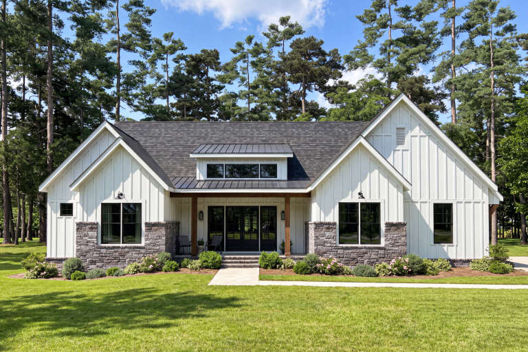Front view of a white house, board-and-batten siding, stone base, dark roof, wood porch posts, and black window frames. House Plan # 009-00535