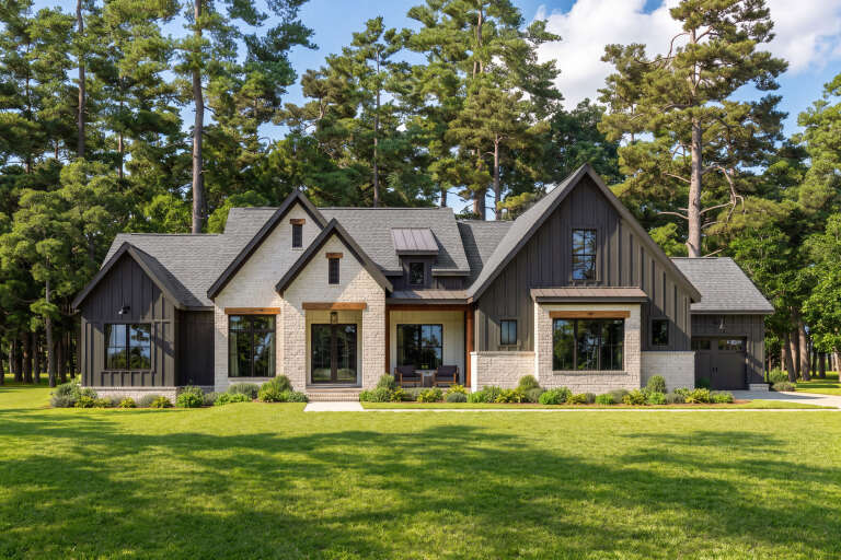 Front view of a black and white house in Modern Transitional style, brick and vertical siding, gabled roof, lush lawn. House Plan # 009-00537