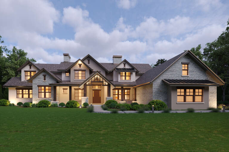 Beige Craftsman Front Elevation, stone and siding, lit windows, gabled roof, lush landscaping, and illuminated pathway. House Plan # 5631-00352 Digital Rendering by America's Best House Plans, Inc.
