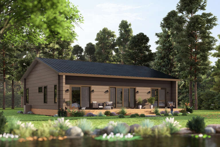 Angled rear view of a brown house in Ranch style, metal roof, wood deck, sliding glass doors, and wooded backyard. House Plan # 3822-00048