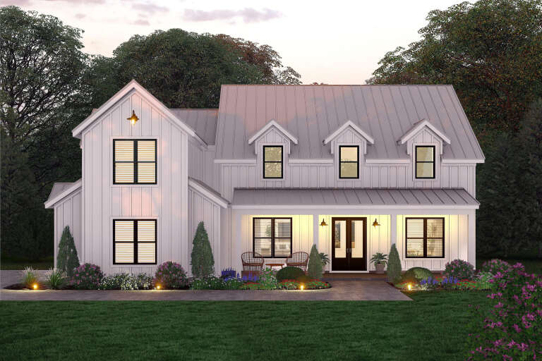 Front view of a white house in Modern Farmhouse style, metal roof, dormers, black windows, and illuminated front porch. House Plan # 940-01482