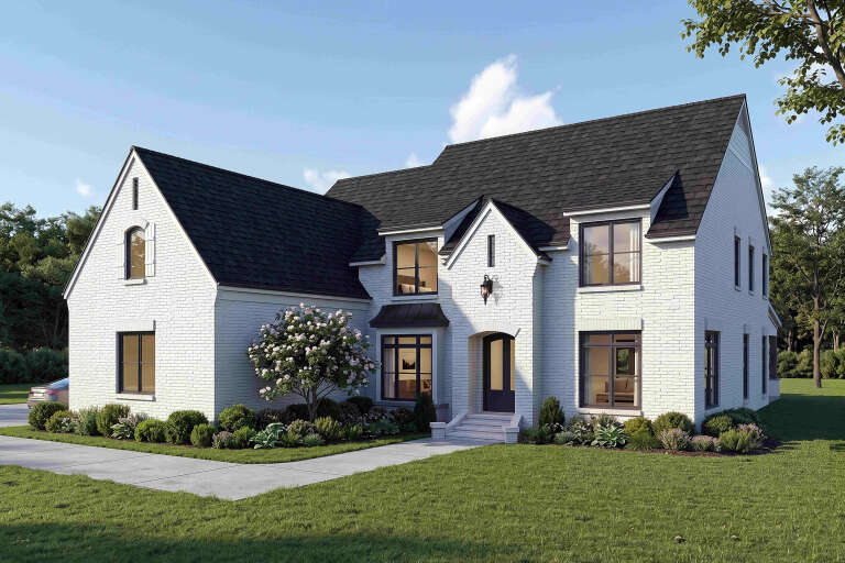 Angled front view of a white house in French Country style, dark roof, brick siding, black windows, and arched entryway. House Plan # 940-01483