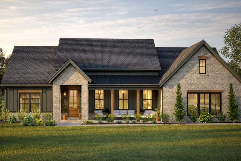Front view of a grey Modern Farmhouse, stone and siding, dark roof, wood porch posts, and illuminated entry. House Plan # 2080-00006