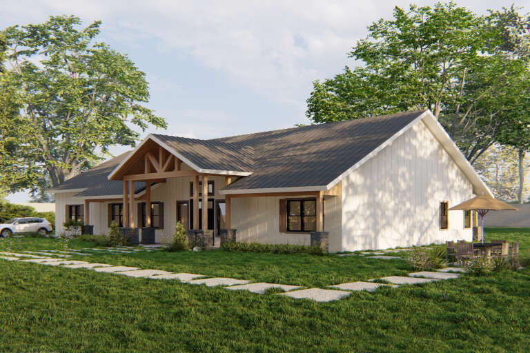 Angled front view of a white house, board-and-batten siding, metal roof, timber porch trusses, and stone column bases. House Plan # 3822-00062