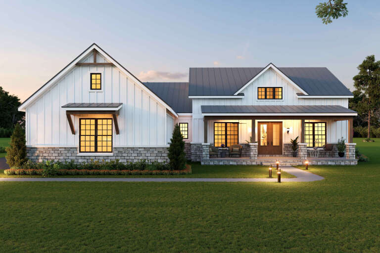 Front view of a white house in Modern Farmhouse style, board-and-batten siding, stone base, metal roof, and front porch. House Plan # 940-01500