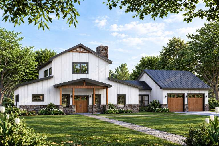 Angled front view of a white house in Barndominium style, board-and-batten siding, stone base, wood doors, metal roof. House Plan # 3822-00072