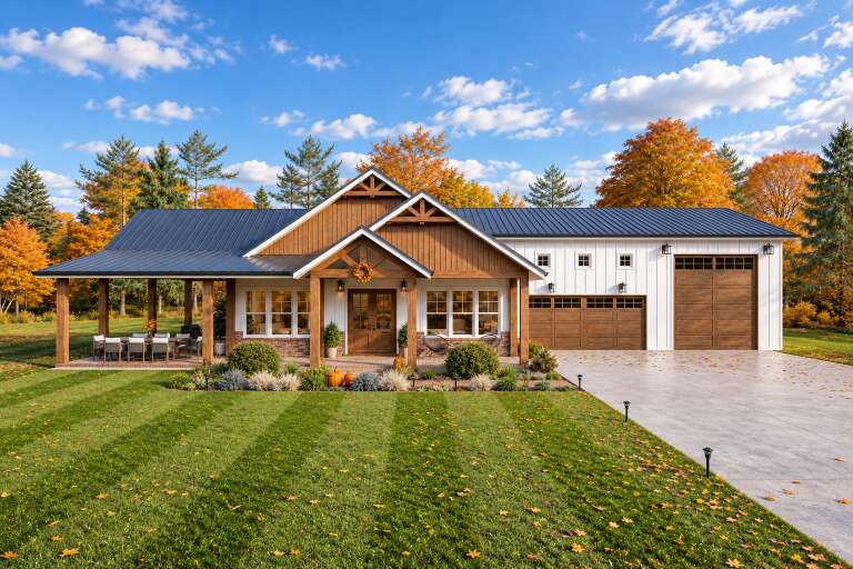 Front view of a white and wood Barndominium house, metal roof, covered patio, brick base, and three-car garage. House Plan # 7174-00047